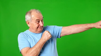 Energetic senior man practicing boxing moves on vibrant green screen, perfect for fitness tutorials or playful health campaigns and active lifestyle content