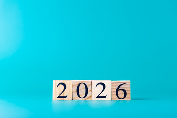 Wooden blocks in a horizontal row showing number 2026 on turquoise blue minimalist background, copy space for graphic design. Copy space. Concept of new year and digital future