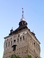 Obraz premium Tall, stone tower of the Evangelical Lutheran Church in Saschiz, Romania, showcasing Transylvanian architecture. Features a pointed steeple with smaller spires at each corner. 
