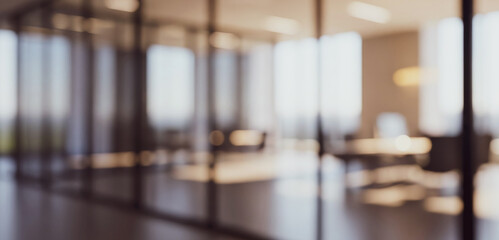 Blurred view of a modern office interior with glass walls and furniture, minimalist design elements and bright daylight creating a professional workspace ambience.