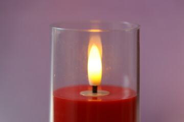 A single red candle is lit inside a clear glass container, perfect for romantic dinner or intimate atmosphere