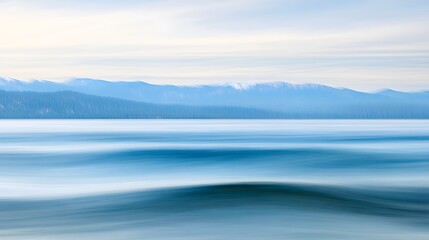 Fototapeta premium Serene Blue Water and Distant Snow- Capped Mountains