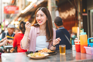 Young adult traveler woman enjoy eating street food spicy thai tasty menu travel at chinatown...