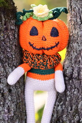 A plush pumpkin perched atop a tree branch, perfect for fall or Halloween decorations