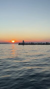 silhouette lighthouse on promenade against sunset over the Adriatic Sea in Zadra, Croatia
