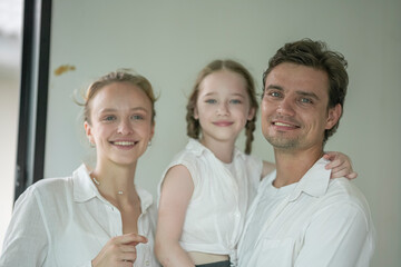 Family portrait featuring parents and daughter indoors with natural light