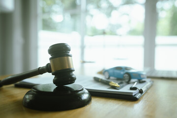 A symbolic scene featuring the scales of justice, a car, a hammer and contract documents...