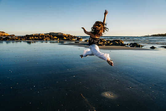 Dancer jumping on the beach at sunset showing freedom and happiness
