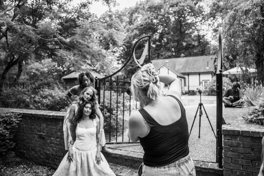 Photographer taking photos of three fashion models in garden