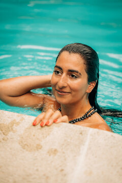 Beautiful woman relaxing in turquoise swimming pool on summer vacation