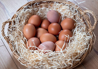 Basket full of eggs with straw in it. There are 12 eggs in the basket.