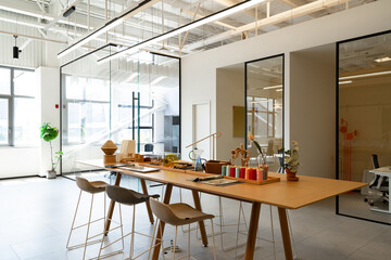 Modern office space with a long table, stools and glass partitions