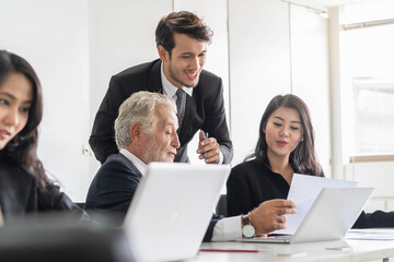 Group of business people sharing ideas. Mature businessman giving guidance to young trainee and...