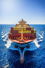 Front view of a large industrial container cargo ship sailing with speed over the ocean