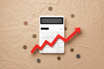 A calculator with a red zigzag upward arrow on a craft paper background, surrounded by scattered...