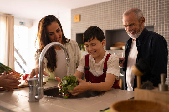 Mother son and grandparents cooking together in kitchen