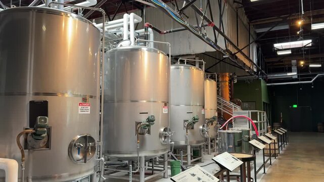 Large, stainless steel whisky fermentation tanks or washbacks at a brewery or distillery with no people - panning reveal