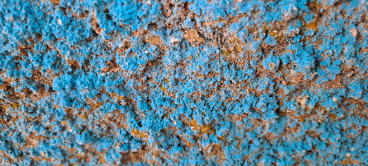 Close-up of an old painted blue concrete wall with rough texture, peeling paint, uneven and grungy...
