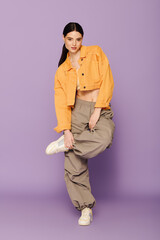 A beautiful woman showcases trendy fashion while playfully posing with one leg raised.