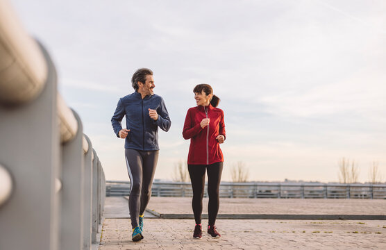 Mature man and woman running on sunny day
