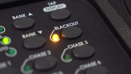 Man activates Blackout mode: close-up of button press on lighting console with blinking LED. 4K