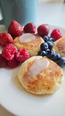 Cheese pancakes with condensed milk served with fresh strawberries, raspberries and blueberries