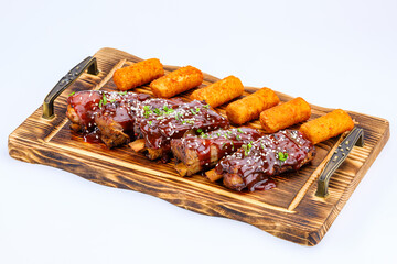 Tantalizing BBQ ribs, glazed with succulent sauce and sesame, served alongside potato croquettes on an elegant serving tray, showcasing ideal cuisine presentation for culinary appreciation.