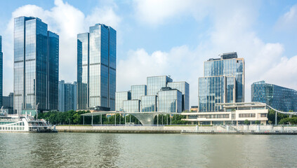Naklejka premium Modern Skyscrapers Along Urban Riverfront with Clear Sky