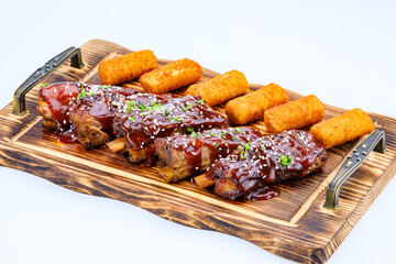 Tantalizing BBQ ribs, glazed with succulent sauce and sesame, served alongside potato croquettes on an elegant serving tray, showcasing ideal cuisine presentation for culinary appreciation.