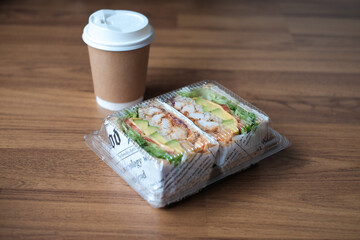 sandwich with filling in a plastic box with coffee in the morning.