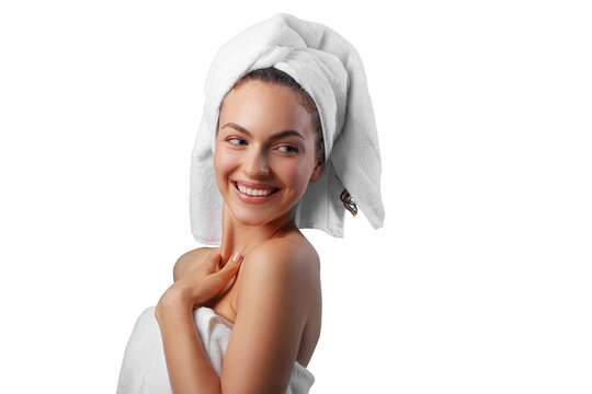 Smiling young woman applying facial cream under her eyes, wrapped in a white towel with a towel turban on her head. PNG with transparency	