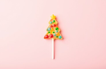 Christmas tree lollipop with colorful candy on top on pink background. Holiday sweets and dessert for greeting card. New Year treat.