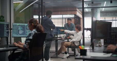 Creative Team of Diverse Specialists Having a Conversation at a Workplace Next to Computer. Two Male Software Engineers and a Female Developer Discussing a Software Code for Their Digital Project - Powered by Adobe