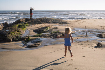 girl in swimsuit running on sandy beach during summer holidays in Portugal