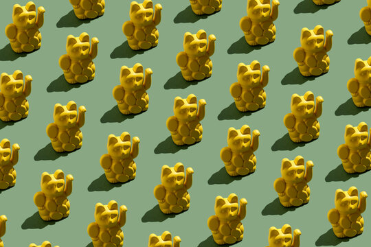 Many yellow Maneki-neko figurines as seamless repeating lucky pattern
