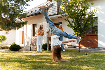 Girl doing cartwheel in garden while family applauding