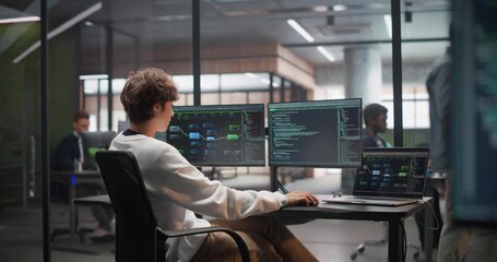 Close Up of a Display with Software Source Code. Slide to a Young Female Sitting with Her Back to Camera, Working on a Desktop Computer, Writing Code and Managing Projects for a Corporate IT Client