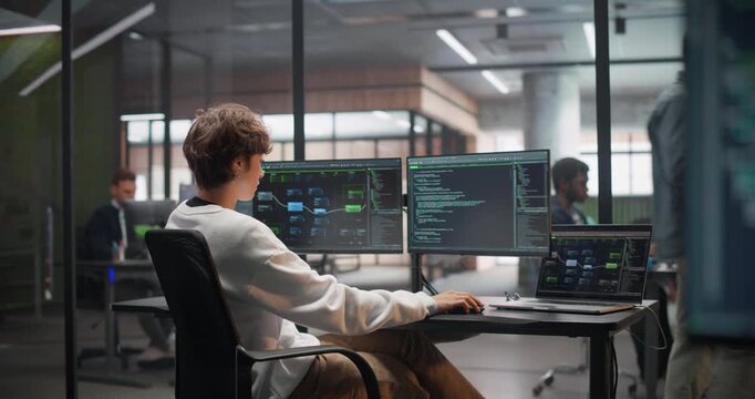 Close Up of a Display with Software Source Code. Slide to a Young Female Sitting with Her Back to Camera, Working on a Desktop Computer, Writing Code and Managing Projects for a Corporate IT Client