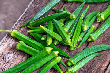 Lady Fingers or Okra over wooden table background. Raw Green Organic Okra Harvest Ready to Cook With. Close up Farm fresh okro on wooden rustic table.