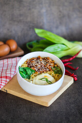 Ramen bowl with egg, vegetables and sesame seeds styled with raw ingredients background