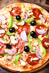 Pizza with chorizo ​​sausage, mozzarella cheese, green pepper and black olives. Rustic wooden background. Soft focus.	
