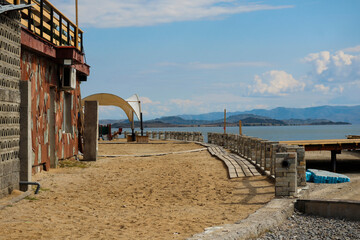 Stone house with terrace and gazebo at Bukhtarma Reservoir resort in early autumn. Yellow sand and lake shore create a cozy and relaxing atmosphere for vacation and leisure