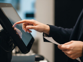 Hands operate touch screen while holding transaction payment receipt.