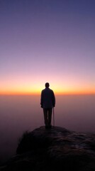 Elderly person gazing at a breathtaking sunset from a rocky outcrop on a calm evening