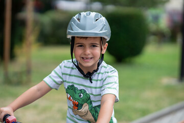 Little kid boy ride a bicycle in the park. Kid cycling on bicycle. Happy smiling child in helmet riding a bike. Boy start to ride a bicycle. Sporty kid bike riding on bikeway. Kids bicycle.