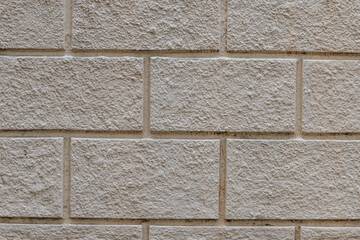Textured surface of light brown brick wall made of decorative concrete. Background with smooth masonry and rough plaster. Brick texture close-up
