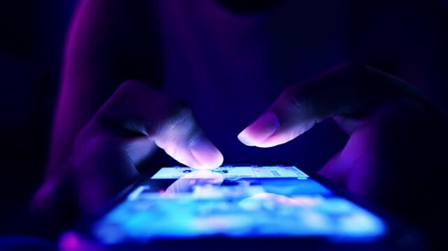 Closeup of woman touching scroll fast on her phone screen, text with friends or use social media in darkness. Female fingers touch screen of smartphone 