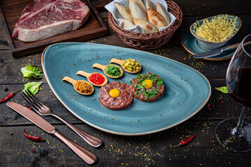 Beef tartare made from chopped dry aged steak in a plate on rustic brown wooden background.
