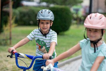 Obraz premium Two confident youngsters enjoy a bike ride in the city, showcasing their friendship and joy. The image highlights health and the importance of safety measures like wearing helmets. 