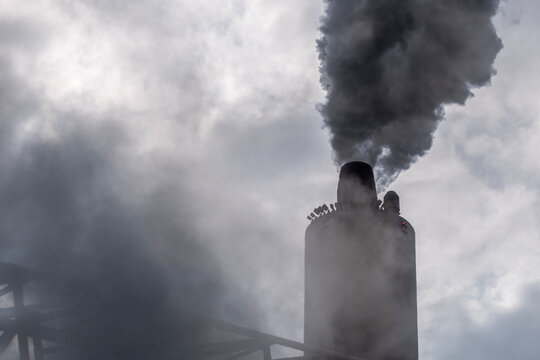 Wide industrial panorama of Copenhagen coastline with plant chimney and offshore wind turbines, visualizing contrast between fossil industry and renewable urban planning future